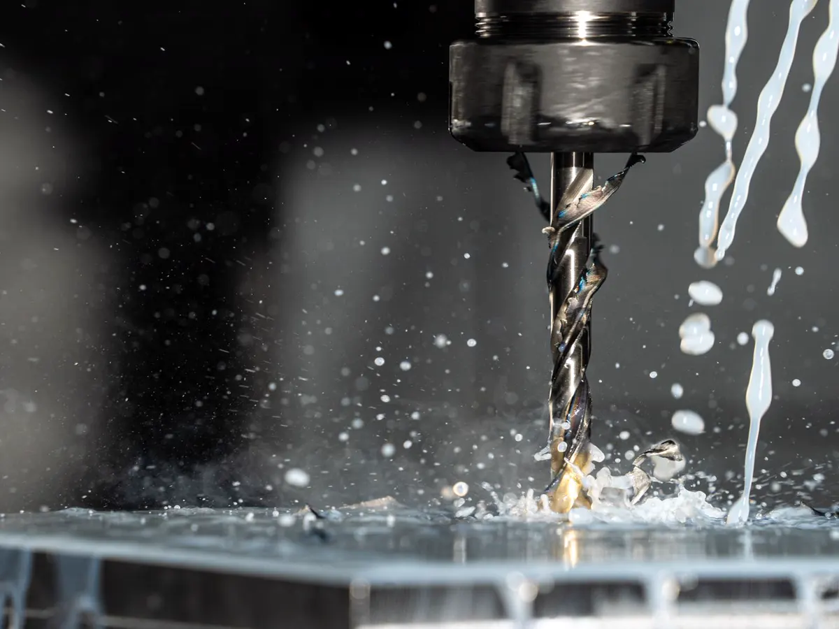 Drill working on a metal part with coolant